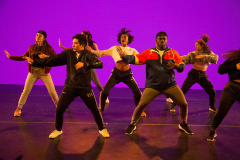 Members of Rhythmic Blue perform against a purple backdrop